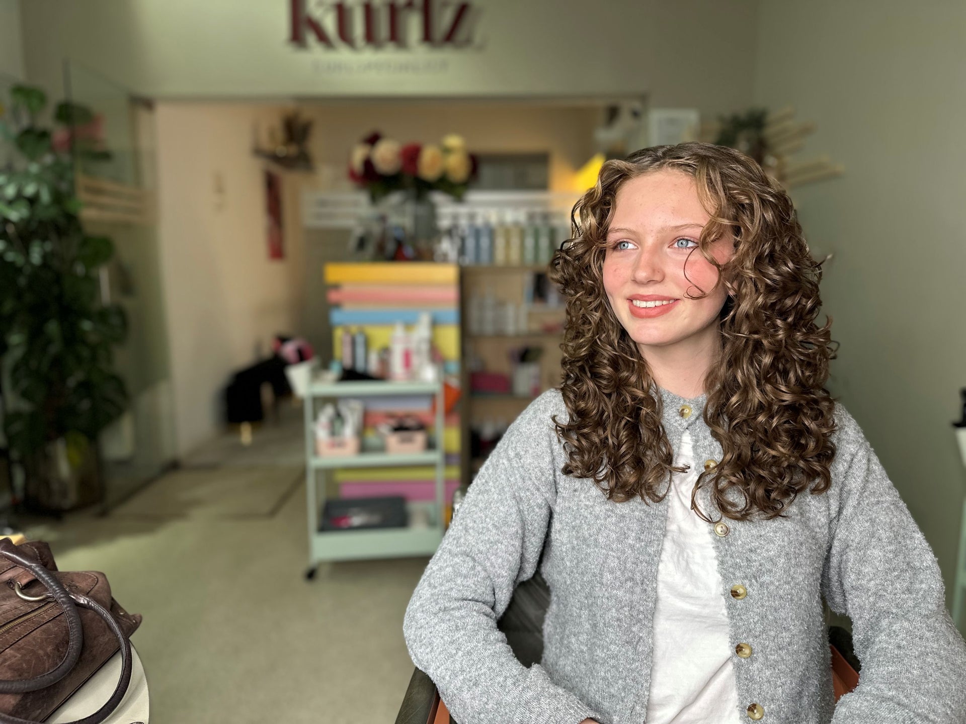 Jong meisje met bruine krullen glimlacht