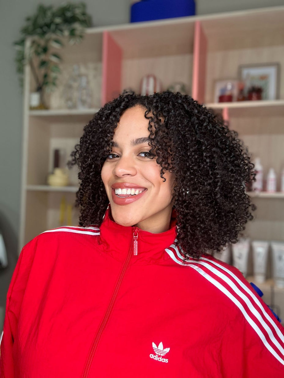 Vrouw met coily krullen draagt een rood vest